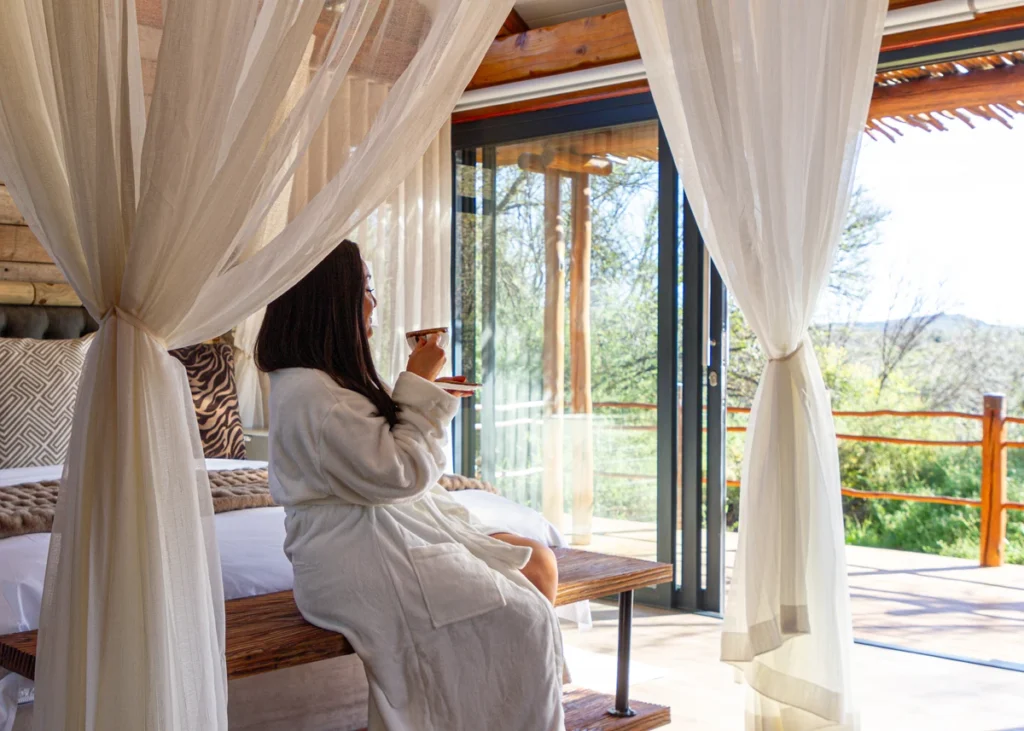 Guest enjoying morning coffee on the terrace of a private suite at Mont Eco Private Nature Reserve, overlooking peaceful bushveld scenery.